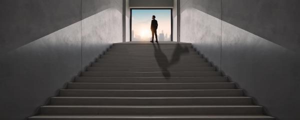 Un homme seul en haut d'escalier dans une atmosphère grise 